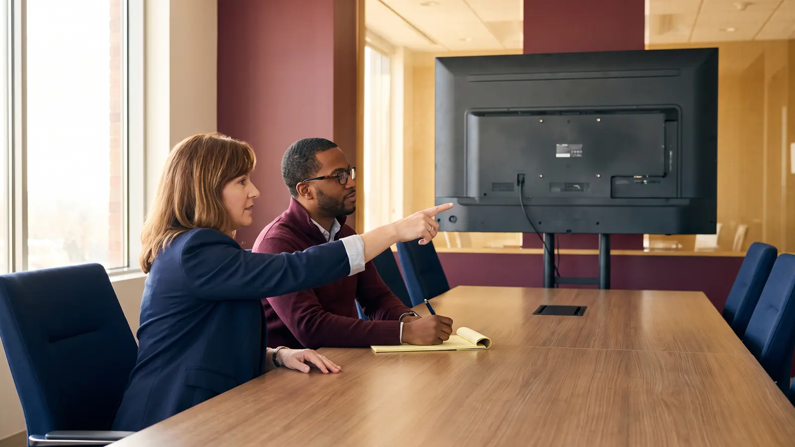 Two logistics staff comparing transportation management software options at a conference table